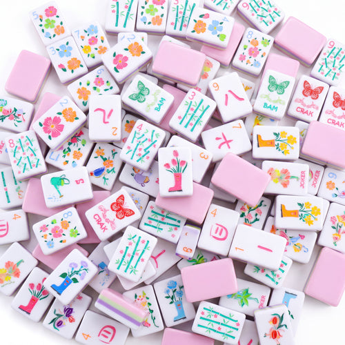 Bloomsbury American mahjong tiles scattered face up and face down, showing pastel pink backs and purple and green layered edges