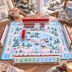 Holly mahjong tiles set up for a game on a winter village mat on a snowy porch