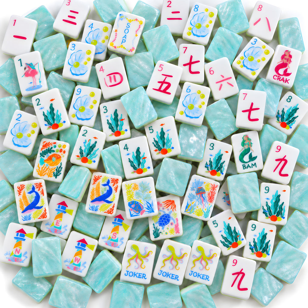 Mermaid American mahjong tiles scattered face up and face down, showing pearly aqua backs