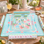Mermaid American mahjong tiles set up for a game on an aqua seashell mat on a sunny terrace, with pearly aqua tile walls and racks