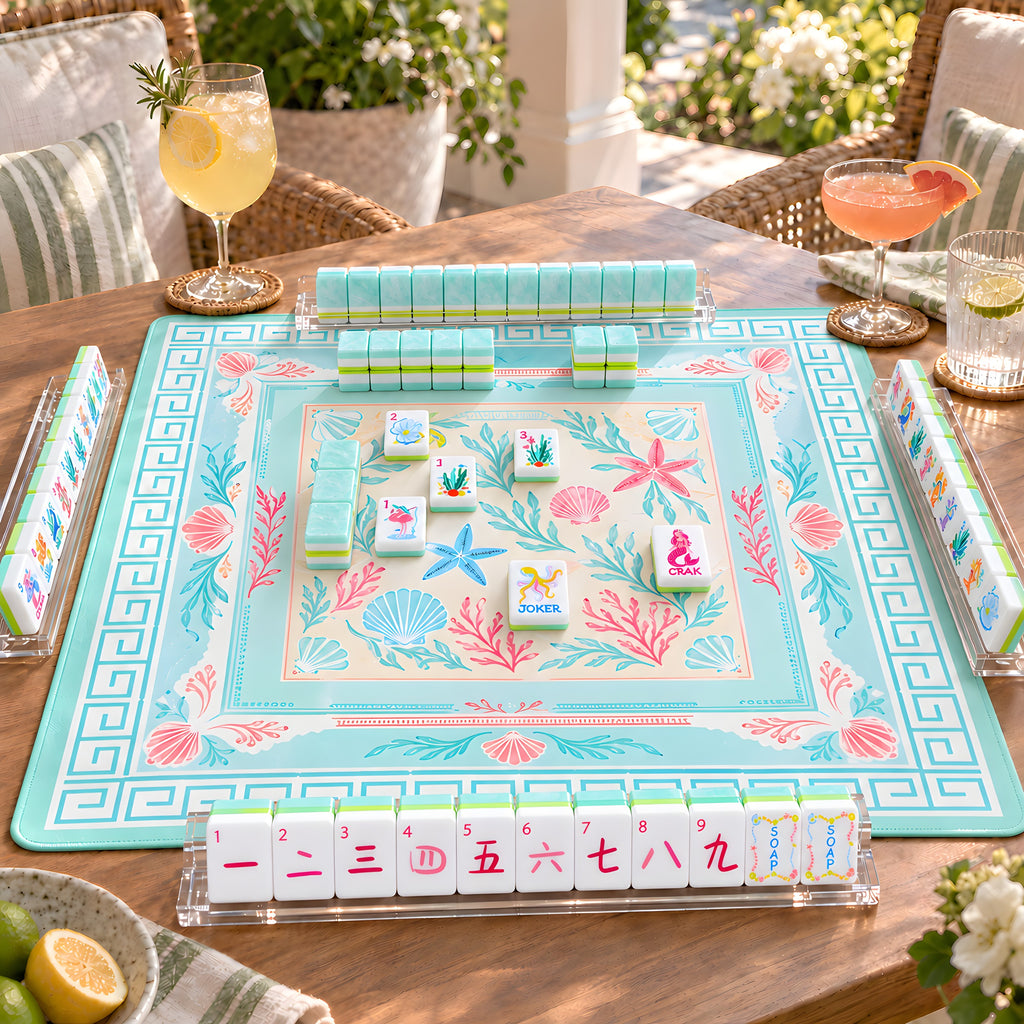 Mermaid American mahjong tiles set up for a game on an aqua seashell mat on a sunny terrace