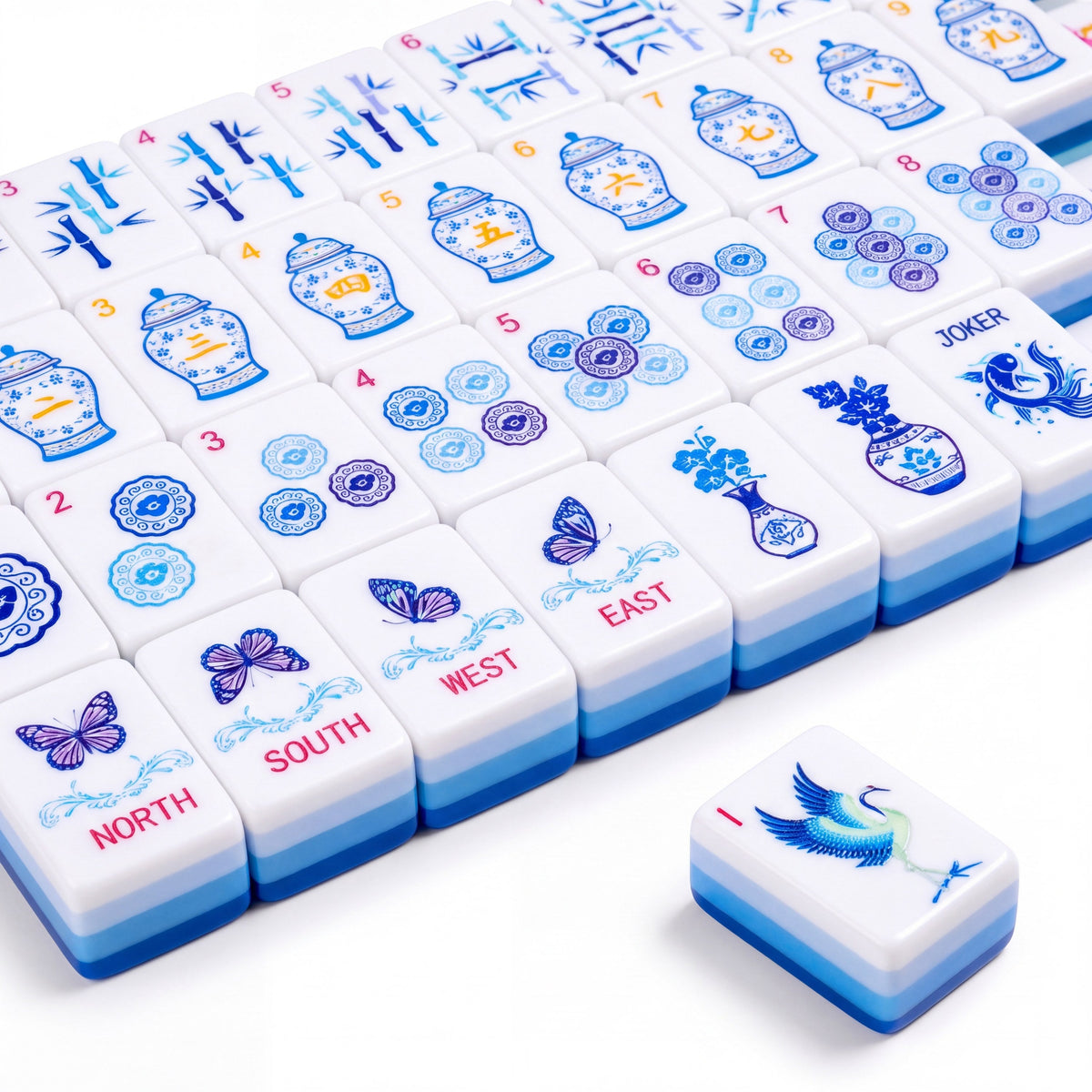 Porcelain American mahjong tiles in rows, showing the blue and white ginger jar craks, bamboo bams, porcelain medallion dots, butterfly winds and the crane joker