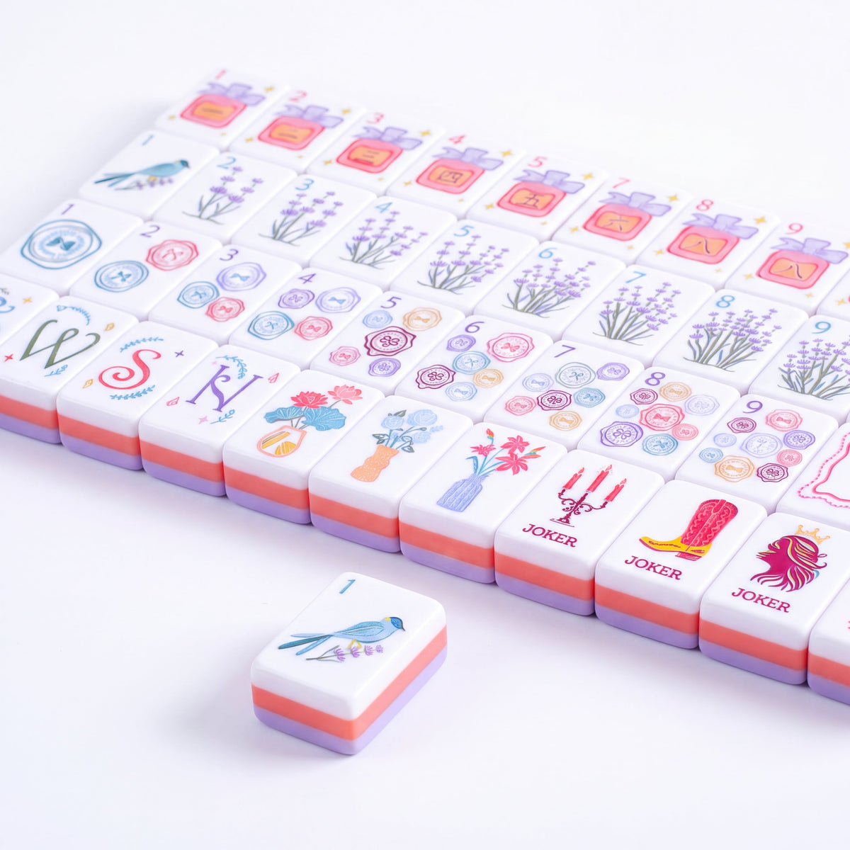 Violette mahjong tiles laid flat in rows with the candlestick, cowboy boot and cocktail jokers in the front row